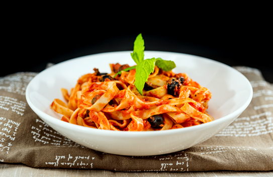 Pasta mat Tomatenszooss an Oliven op Dësch